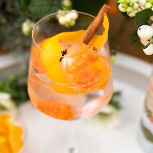 Example image of a colorful orange drink on a white table with dark leaves in the background.